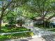 Charming single-story home featuring lush landscaping, a two-car garage, and a welcoming red front door at 1187 Mistwood Dr, Tarpon Springs, FL 34688