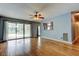Spacious living room featuring wood laminate flooring, ceiling fan, sliding glass door access, and passthrough to kitchen at 16403 Bonneville Dr, Tampa, FL 33624