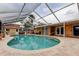 Screened-in pool with brick paver patio and view of the backyard at 16403 Bonneville Dr, Tampa, FL 33624