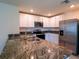 Modern kitchen features stainless steel appliances, granite countertops, and white cabinetry at 16805 Delia St, Wimauma, FL 33598