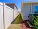 Neat side yard with a white privacy fence, rock beds, and partial grass at 16805 Delia St, Wimauma, FL 33598