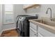 Well-equipped laundry room featuring a sink, modern washer and dryer, and natural light at 26920 Winged Elm Dr, Wesley Chapel, FL 33544