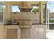 Close up of outdoor kitchen area featuring stone counter, built in grill and stainless steel appliances at 26920 Winged Elm Dr, Wesley Chapel, FL 33544