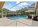 Enclosed pool area with ample deck space, an umbrella, and a glimpse of the surrounding neighborhood at 26920 Winged Elm Dr, Wesley Chapel, FL 33544