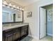 Bathroom featuring a double vanity with granite countertop, dark cabinets, and decorative mirror with modern lighting at 28642 Tranquil Lake Cir, Wesley Chapel, FL 33543