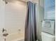 Bright bathroom featuring a tub with shower and a grey curtain for privacy, with a convenient toilet and towel bar at 28642 Tranquil Lake Cir, Wesley Chapel, FL 33543