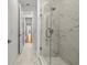 Elegant bathroom featuring a marble tiled shower and floors, complemented by a bright hallway view at 33736 Ocean Spray Ln, Wesley Chapel, FL 33543