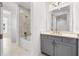 Elegant bathroom featuring marble tile, a tub with shower, and gray vanity with gold fixtures at 33736 Ocean Spray Ln, Wesley Chapel, FL 33543