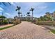 Grand entrance to Sunset Pointe with a brick driveway, lush landscaping, and elegant signage at 755 Collany Rd # 504, Tierra Verde, FL 33715