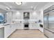 Modern white kitchen with stainless steel appliances, stone backsplash, and light wood flooring at 755 Collany Rd # 504, Tierra Verde, FL 33715