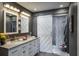 Modern bathroom boasts double sinks, granite counters, sliding barn door shower, and decorative gray wavy wall tiles at 758 Claudia Ln, Palm Harbor, FL 34683