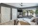 Comfortable bedroom features gray walls, ceiling fan, two closets with patterned doors, and a view of the lush landscape at 758 Claudia Ln, Palm Harbor, FL 34683