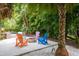 Outdoor patio with pavers features colorful Adirondack chairs around a firepit and lush landscaping at 758 Claudia Ln, Palm Harbor, FL 34683
