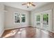 Bright bedroom with hardwood floors, ceiling fan, two windows, and glass panel doors at 933 E Shadowlawn Ave, Tampa, FL 33603