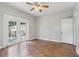 Bedroom with hardwood floors, ceiling fan, glass panel doors, and a door to another room at 933 E Shadowlawn Ave, Tampa, FL 33603