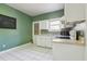 An angled view of a kitchen with white appliances, cabinets, white tile floor, and green walls at 933 E Shadowlawn Ave, Tampa, FL 33603