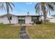 Backyard showcasing a waterfront view, framed by mature trees and a cozy patio area, and a well maintained lawn at 11755 7Th E St, Treasure Island, FL 33706