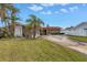 Inviting single-story home featuring stone siding, a red tile roof, and a concrete driveway, with lush green lawn at 11755 7Th E St, Treasure Island, FL 33706