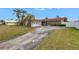 Well-maintained home featuring stone accents, a red tile roof, attached garage, and a spacious concrete driveway and front lawn at 11755 7Th E St, Treasure Island, FL 33706