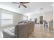 Open-concept living room with large gray sectional, tile floors, and lots of natural light through the windows at 12639 Lemon Pepper Dr, Riverview, FL 33578