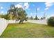 Spacious backyard with healthy grass, a full white fence, and mature palm trees at 14426 Haddon Mist Dr, Wimauma, FL 33598