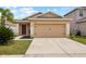 Front exterior view of home featuring a two-car garage, well-kept lawn, and neatly trimmed bushes at 14426 Haddon Mist Dr, Wimauma, FL 33598