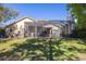Home's backyard showcases a screened-in pool, a spacious lawn and lush trees at 14809 Tudor Chase Dr, Tampa, FL 33626