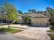 Beautiful home featuring lush landscaping, a red front door, stone accents, and a paver driveway at 14809 Tudor Chase Dr, Tampa, FL 33626