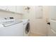 Convenient laundry room with white washer and dryer, overhead cabinets, and a wall-mounted ironing board at 14809 Tudor Chase Dr, Tampa, FL 33626