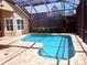 A beautiful screened-in kidney-shaped pool with brick pavers and a view of lush landscaping at 14809 Tudor Chase Dr, Tampa, FL 33626