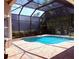 A stunning, screened-in kidney-shaped pool with brick pavers and a view of the surrounding trees at 14809 Tudor Chase Dr, Tampa, FL 33626