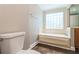 Bathroom showcasing a bathtub with tiled surround, window, and toilet at 16012 Ballica Dr, Tampa, FL 33618