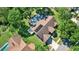 Aerial view of a home with solar panels, a pool, lush green lawn, and mature trees at 17108 Longacres Ln, Odessa, FL 33556