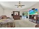 Bedroom view with a large TV, ceiling fan, and sliding doors leading to the pool area at 17108 Longacres Ln, Odessa, FL 33556