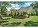 Charming single-Gathering home showcasing lush landscaping and an arched entrance with a red door at 17108 Longacres Ln, Odessa, FL 33556