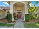 Inviting front entrance featuring a striking red door, manicured landscaping, and an arched entryway at 17108 Longacres Ln, Odessa, FL 33556