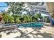 Sparkling screened in pool featuring a spa, surrounded by lush landscaping and a basketball hoop at 17108 Longacres Ln, Odessa, FL 33556