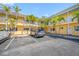 Exterior view of the condo showing parking and a maintained landscape with palm trees at 19417 Gulf Blvd # B-210, Indian Shores, FL 33785