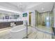 Stunning primary bathroom featuring a soaking tub, chandelier, dual vanity, and glass enclosed shower with dual shower heads at 19816 Gulf Boulevard # 201, Indian Shores, FL 33785
