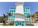 Modern condominium featuring a sleek white facade, turquoise windows, and professionally landscaped entrance at 19816 Gulf Boulevard # 201, Indian Shores, FL 33785