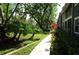 Exterior side view of the home with tropical foliage, grassy lawn and sidewalk at 2101 Fox Chase Blvd # 102, Palm Harbor, FL 34683