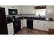 Well-lit kitchen with black appliances, white cabinetry, and a neutral tile backsplash at 2101 Fox Chase Blvd # 102, Palm Harbor, FL 34683