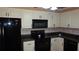 Kitchen featuring modern black appliances, neutral backsplash and bright white cabinets at 2101 Fox Chase Blvd # 102, Palm Harbor, FL 34683