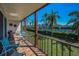 Covered balcony with brick floors and views of the tennis court and palm trees at 3021 Countryside Blvd # 24A, Clearwater, FL 33761