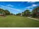 Expansive golf course view with lush green grass, mature trees, and a clear blue sky with light clouds at 3021 Countryside Blvd # 24A, Clearwater, FL 33761