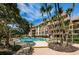 Inviting pool featuring well-manicured landscape and trees, along with a multi-story building and blue sky with white clouds at 3021 Countryside Blvd # 24A, Clearwater, FL 33761
