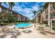 Inviting community pool surrounded by palm trees, tables, and seating areas, set against a backdrop of multi-story buildings at 3021 Countryside Blvd # 24A, Clearwater, FL 33761