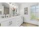 Bright bathroom featuring double sinks, white cabinetry, and modern fixtures at 3323 Ringwood Mdw, Sarasota, FL 34235