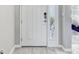 Bright entryway with a white front door, wood-look tile flooring, and a glimpse of the bedroom beyond at 33886 Landsman Loop, Wesley Chapel, FL 33543
