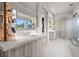 Well-lit bathroom featuring double vanities, modern fixtures, walk-in shower and tile flooring at 5131 W Neptune Way, Tampa, FL 33609